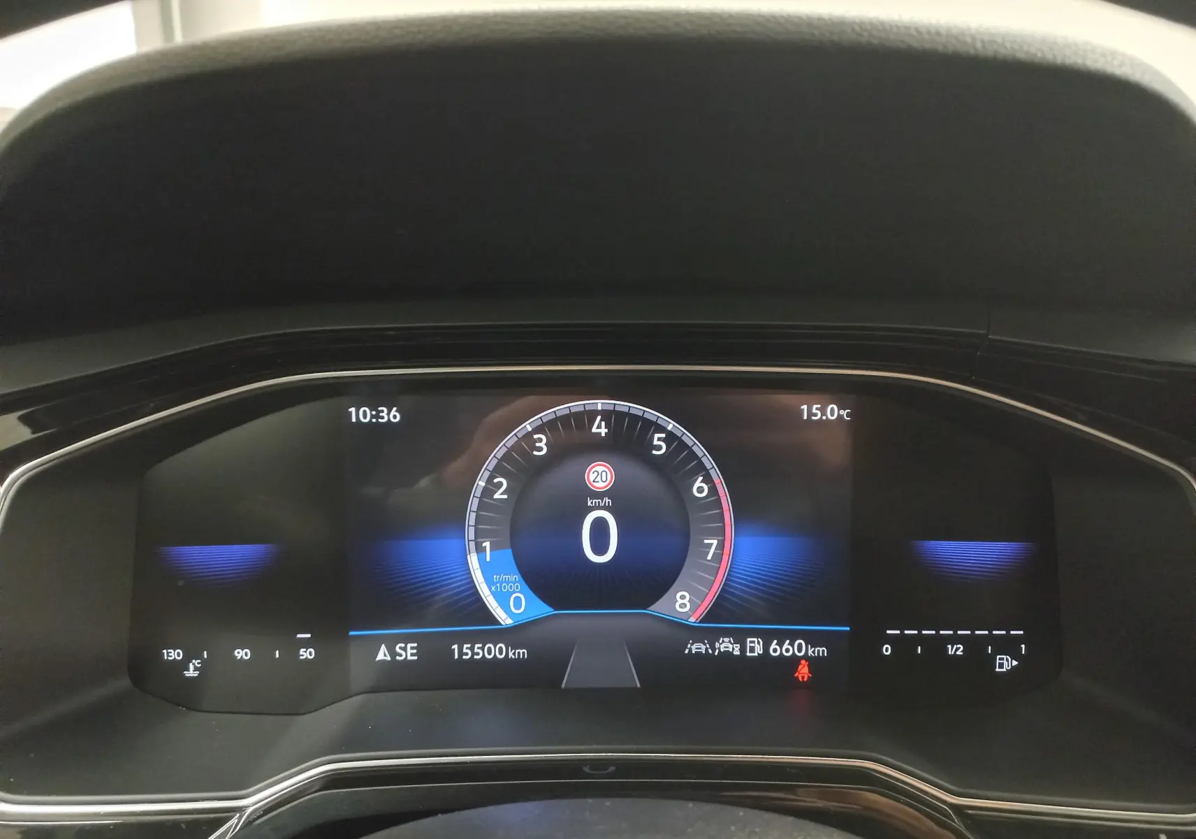 Tableau de bord numérique de Volkswagen Polo blanc, affichant vitesse à 0 km/h et température extérieure 15°C.