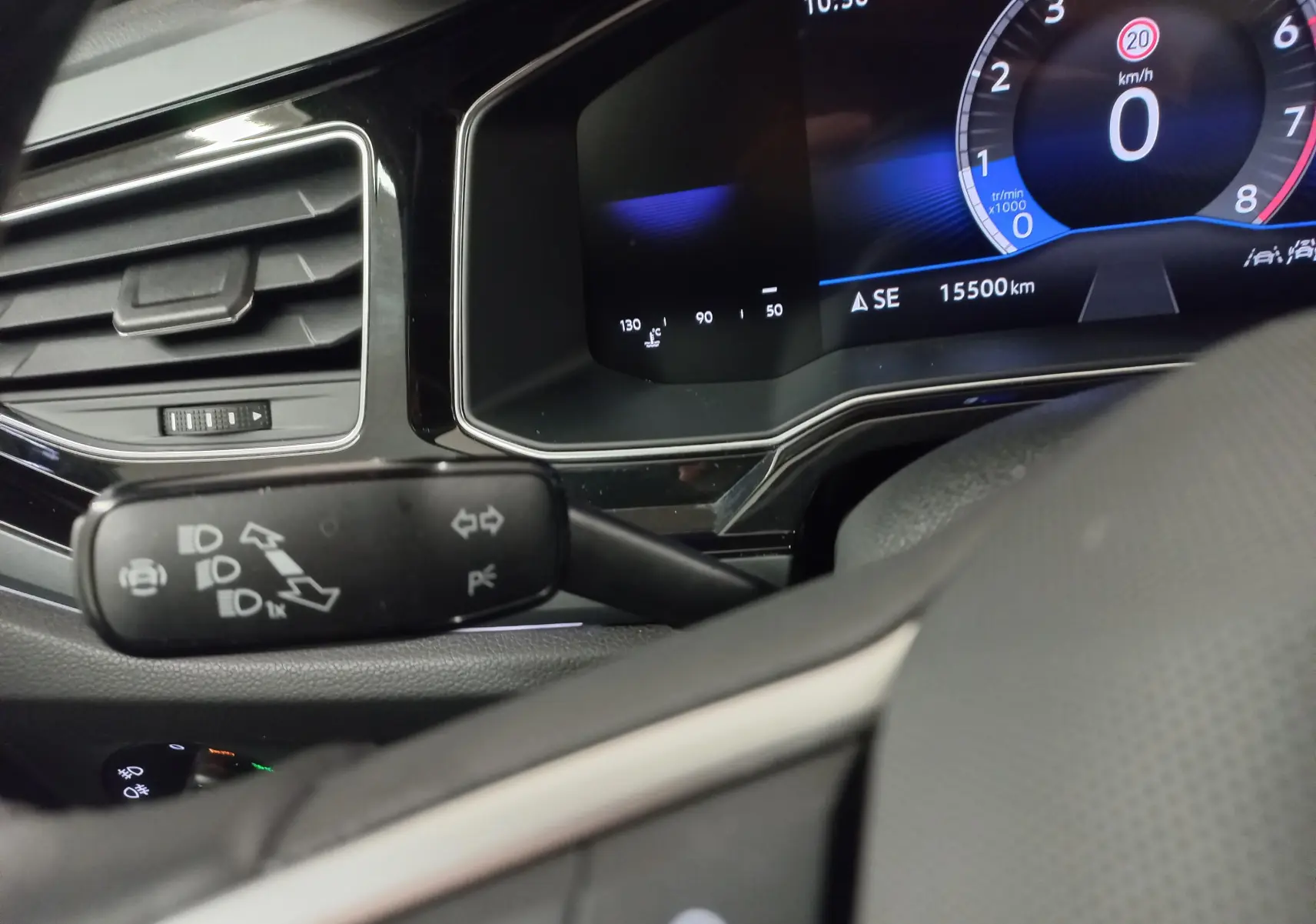 Vue intérieure rapprochée du tableau de bord et du commodo gauche de la Volkswagen Polo 1.0 TSI blanche, affichant le compteur digital.