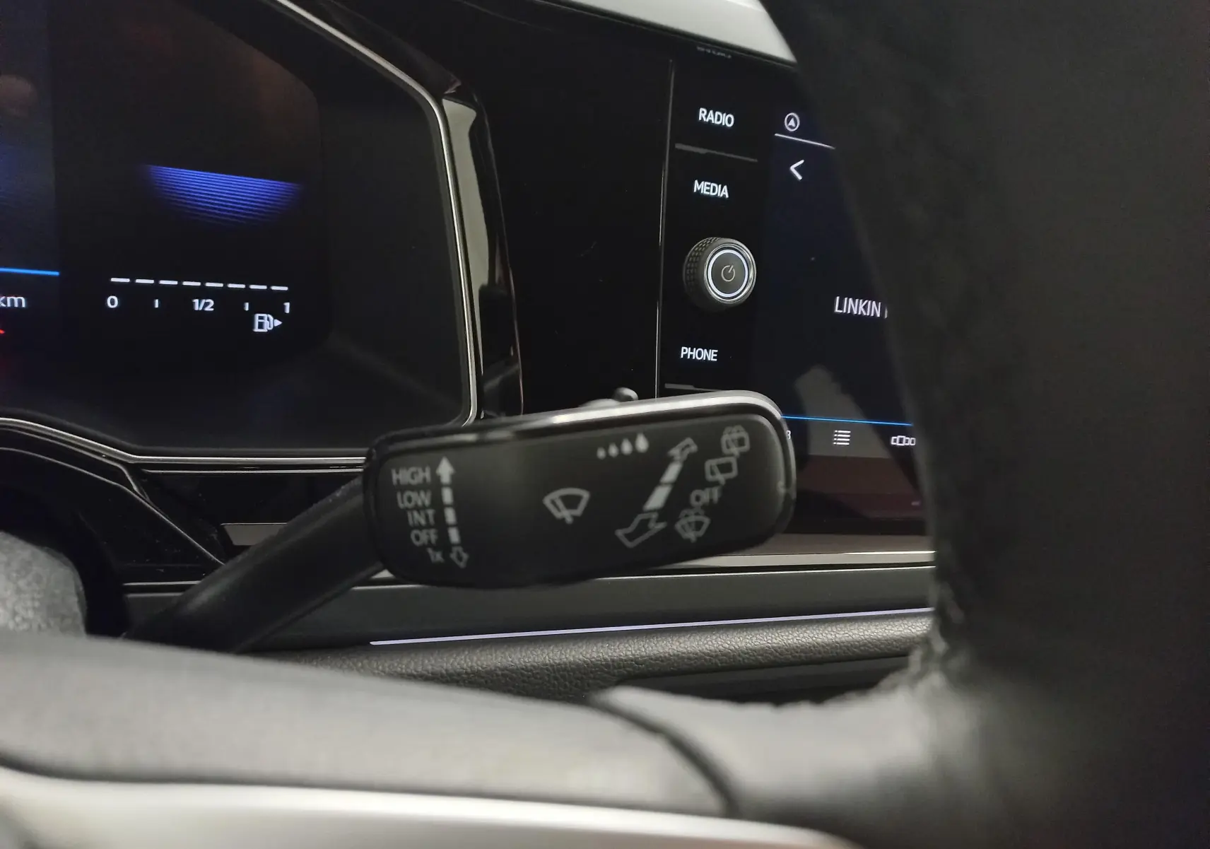 Gros plan sur la commande d'essuie-glace à gauche du volant dans l'habitacle d'une Volkswagen Polo blanche.