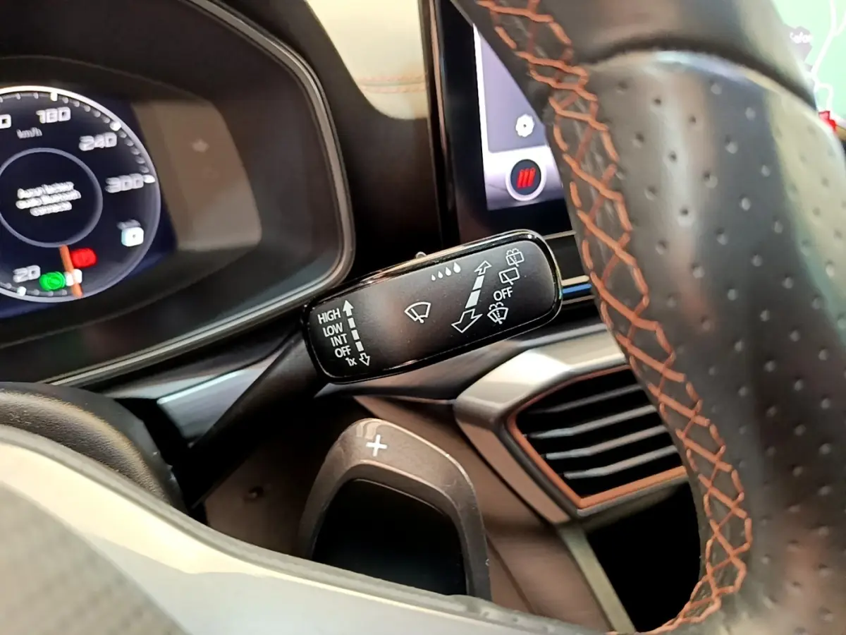 Gros plan sur le volant cuir gris foncé avec surpiqûres orange et commande essuie-glace du CUPRA Formentor 2022.