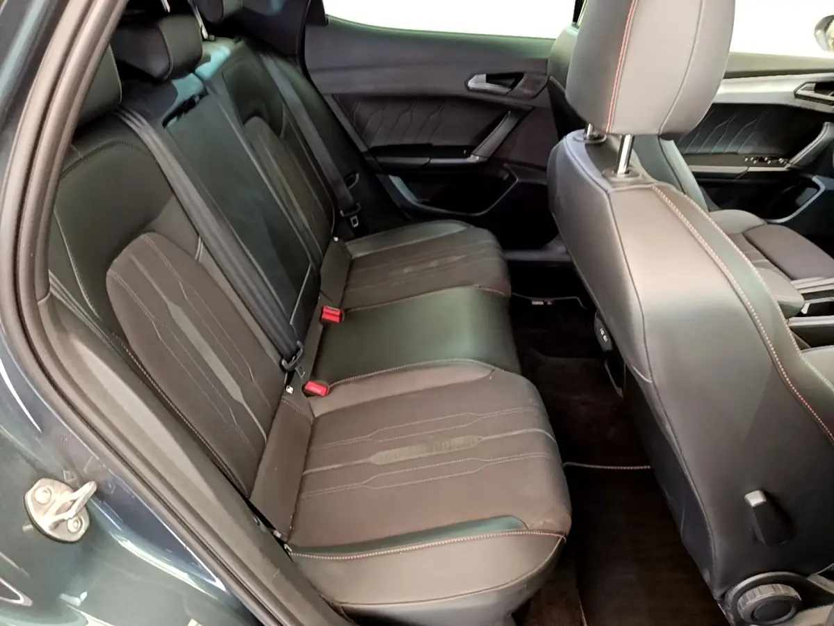 Vue intérieure côté gauche montrant la banquette arrière en cuir noir avec surpiqûres rouges d'une CUPRA Formentor gris foncé.