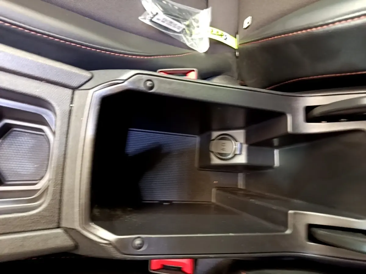 Vue rapprochée de la console centrale noire avec prise 12V et coutures rouges sur les sièges du CUPRA Formentor 2022.
