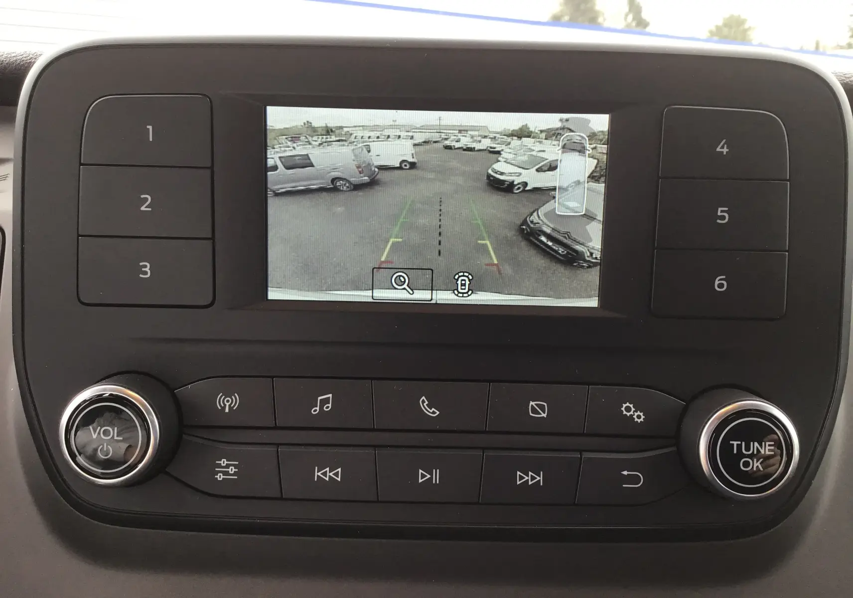 Écran central du Ford Transit Fourgon 2023 montrant la caméra de recul avec vue sur un parking extérieur.