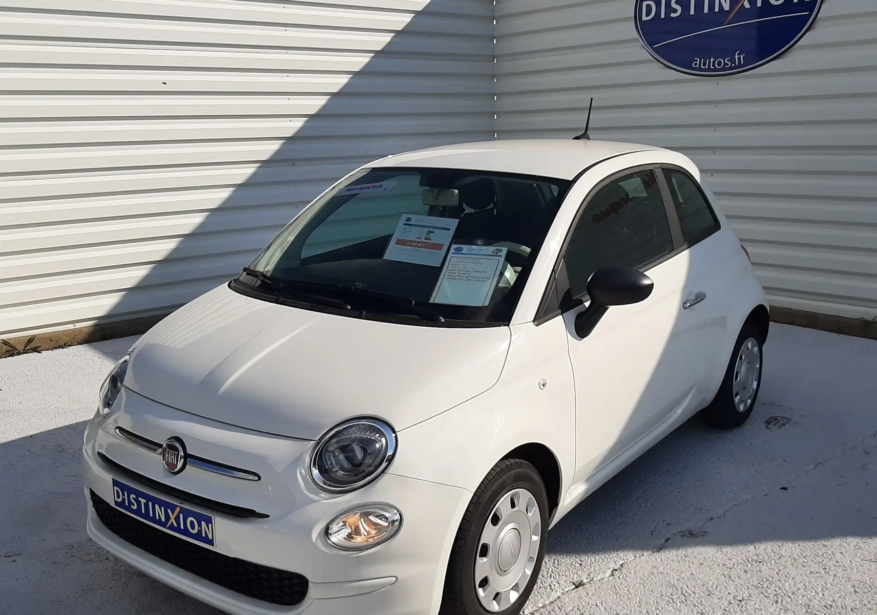 Fiat 500 blanche vue en 3/4 avant droit, compacte avec phares ronds et jantes acier simples.