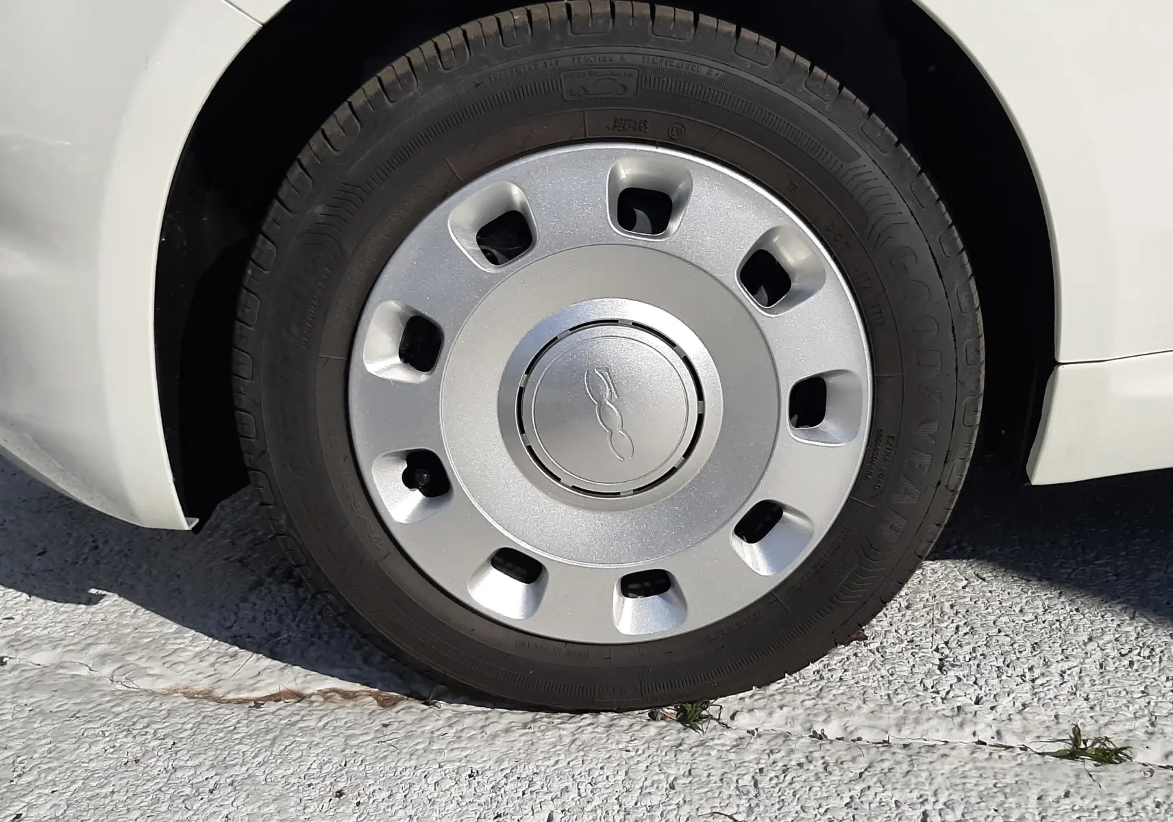 Gros plan sur la roue avant droite d'une FIAT 500 blanche 2023, mettant en valeur la jante avec logo central.