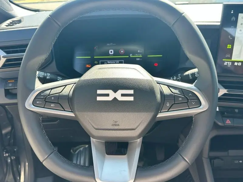 Vue rapprochée du volant multifonction noir du Dacia Bigster 2025, avec tableau de bord numérique en arrière-plan.