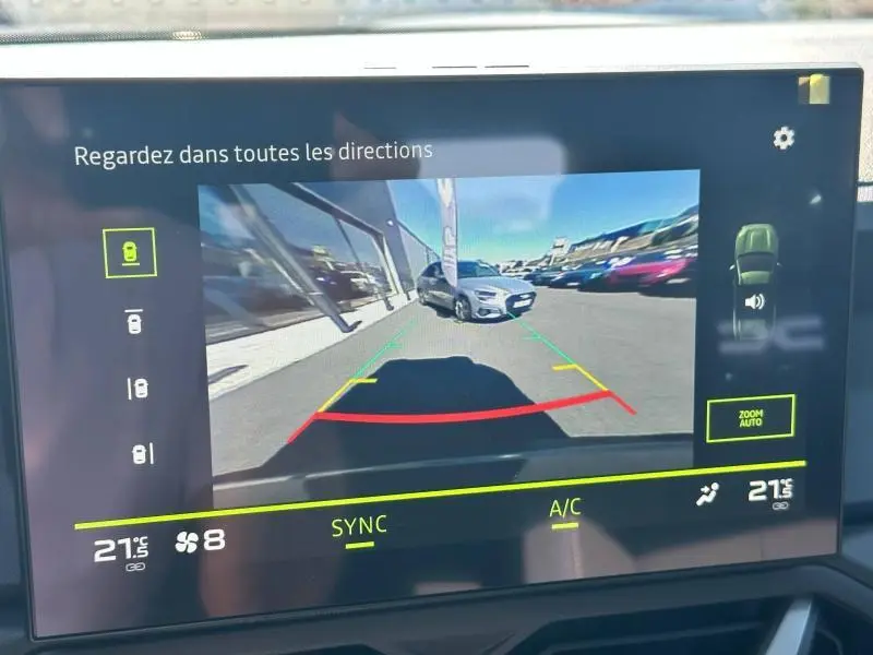 Affichage de la caméra de recul du Dacia Bigster blanc montrant une voiture grise en 3/4 avant sur un parking extérieur.