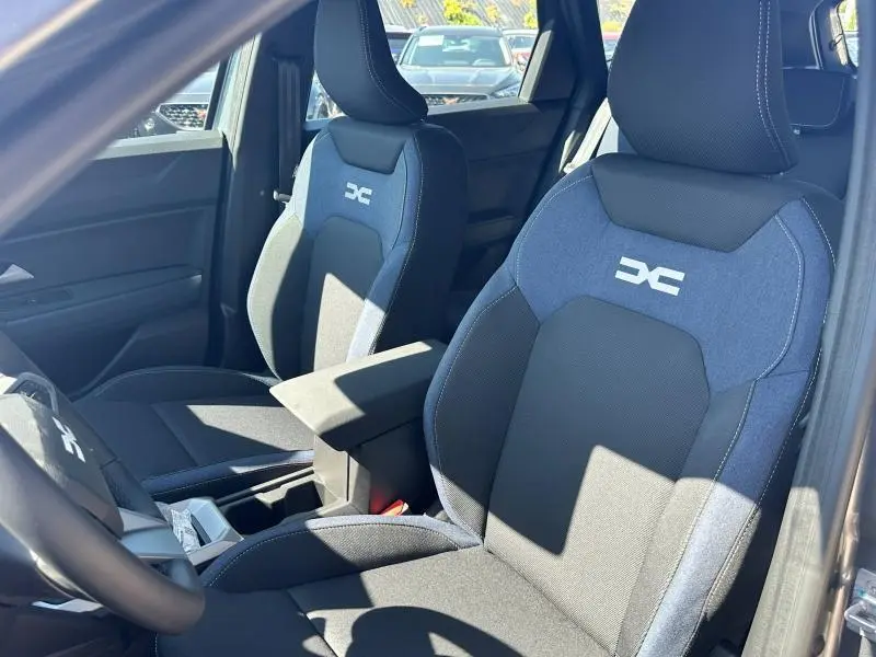 Vue intérieure rapprochée des sièges avant bleu et noir avec logo Dacia sur un DACIA BIGSTER 2025 blanc.