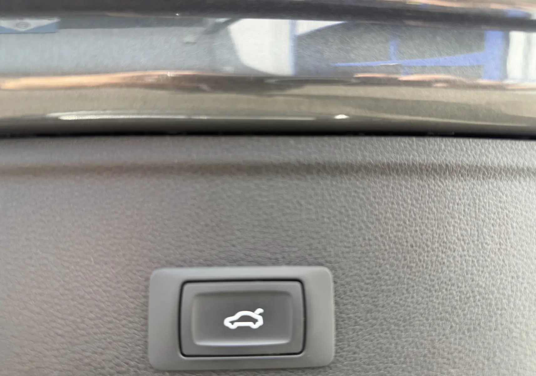 Bouton d'ouverture électrique du coffre sur la garniture intérieure d'une Audi A4 Avant gris Daytona Metal 2023.