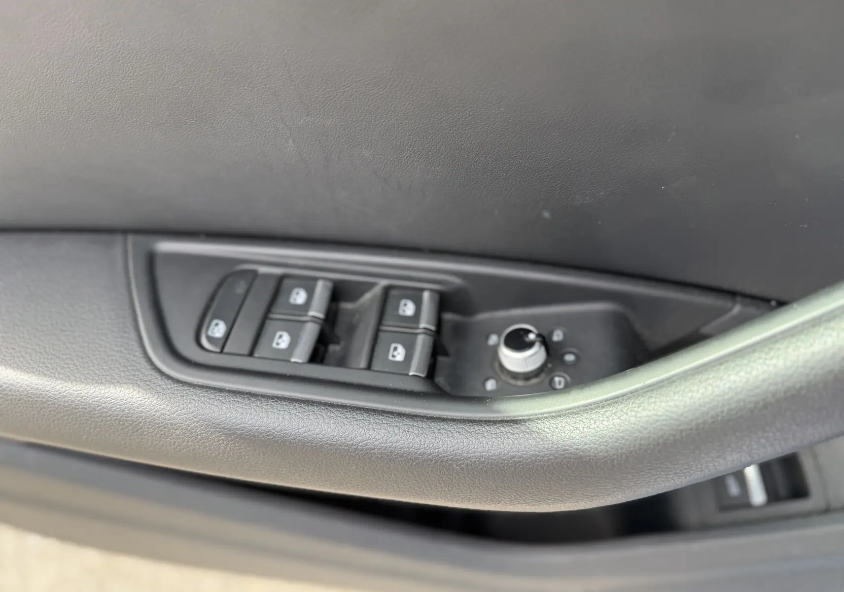 Commandes des vitres et réglage des rétroviseurs sur la porte côté conducteur d'une Audi A4 Avant gris Daytona 2023.