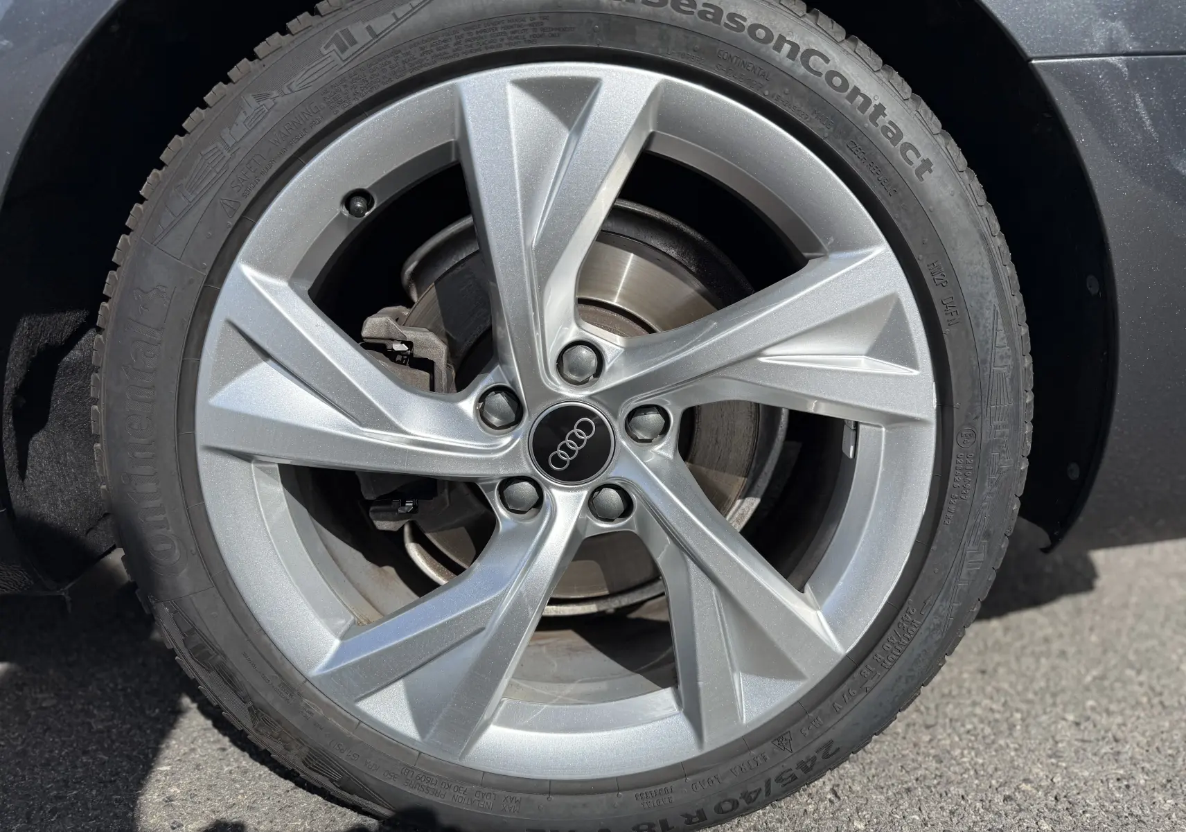 Gros plan sur la jante alliage argentée Audi à 5 branches du pneu Continental AllSeasonContact d'une A4 Avant gris Daytona.