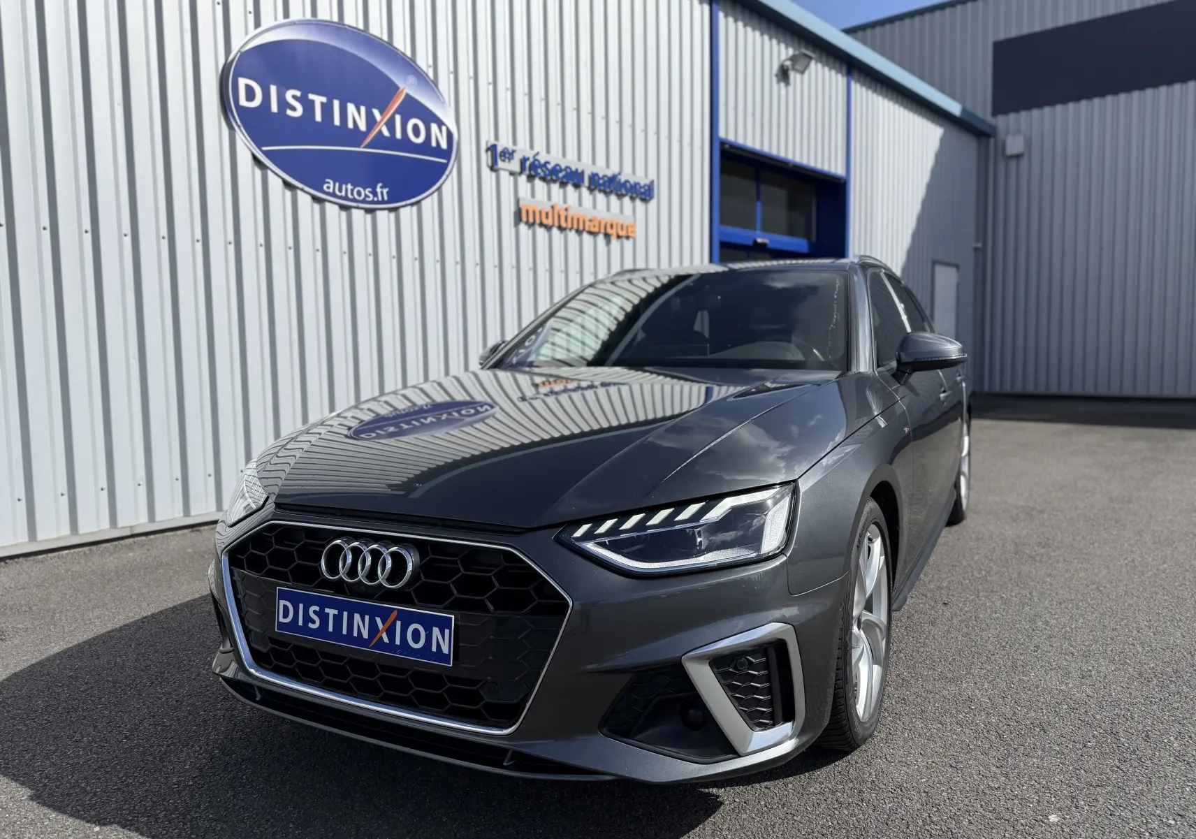 Audi A4 Avant gris Daytona metal vue 3/4 avant droit, mettant en valeur ses phares LED et calandre hexagonale noire.