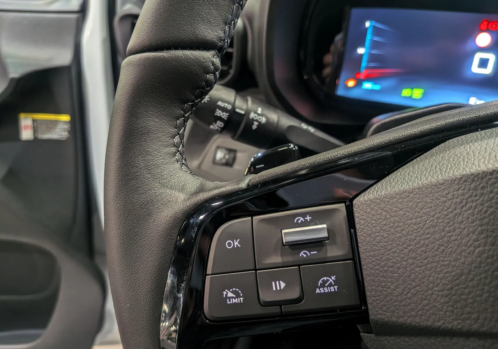 Gros plan sur le volant cuir noir du Citroën Berlingo 2025 avec commandes intégrées et tableau de bord numérique en arrière-plan.