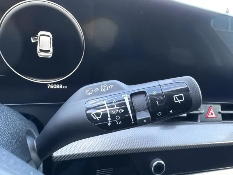 Gros plan sur la commande des essuie-glaces dans l’habitacle noir du Kia Sportage 2022, affichage digital en arrière-plan.