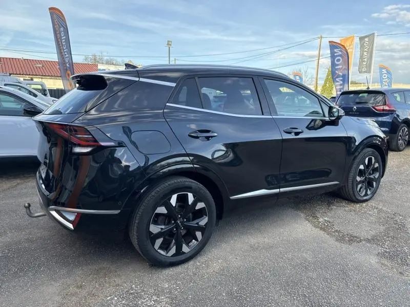 Vue 3/4 arrière droite d'un KIA SPORTAGE noir Basalte métallisé avec jantes alliage et feux arrière LED distinctifs.