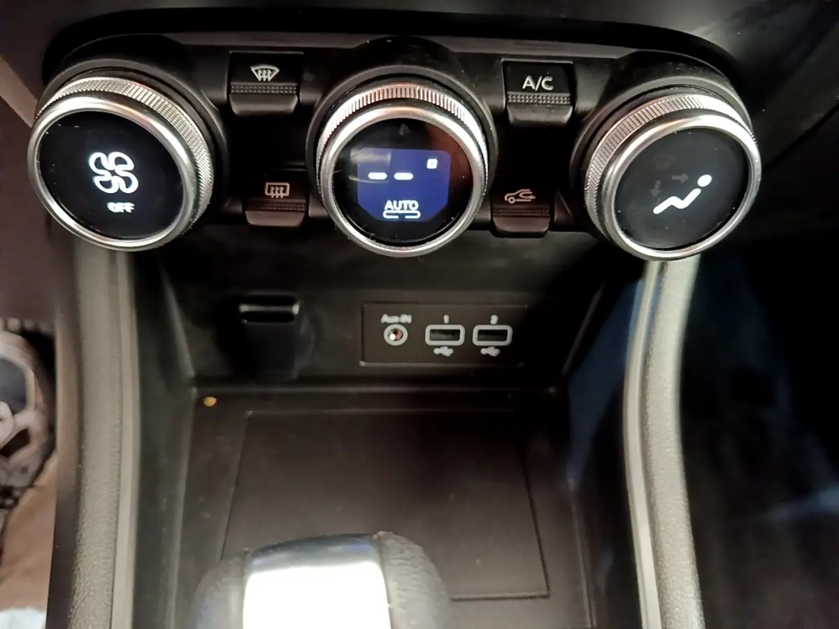 Gros plan sur la console centrale du Renault Captur gris foncé 2022, avec commandes climatisation et ports USB visibles.