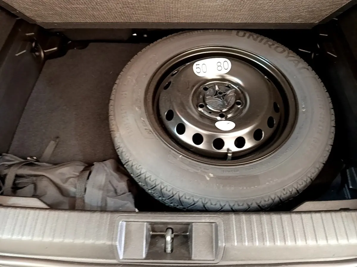 Vue plongeante sur la roue de secours noire dans le coffre du Renault Captur Zen E-Tech hybride gris foncé 2022.