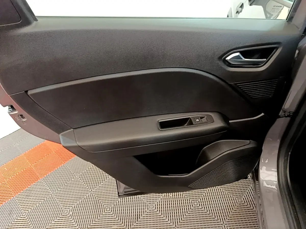 Vue rapprochée de la porte avant droite du Renault Captur gris foncé, montrant la poignée et les commandes de fenêtre.