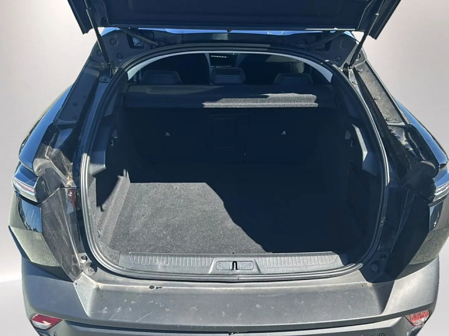 Coffre ouvert d'une Peugeot 408 Hybrid 145 allure e-dcs6 noire, vue arrière montrant l'espace de chargement vide.