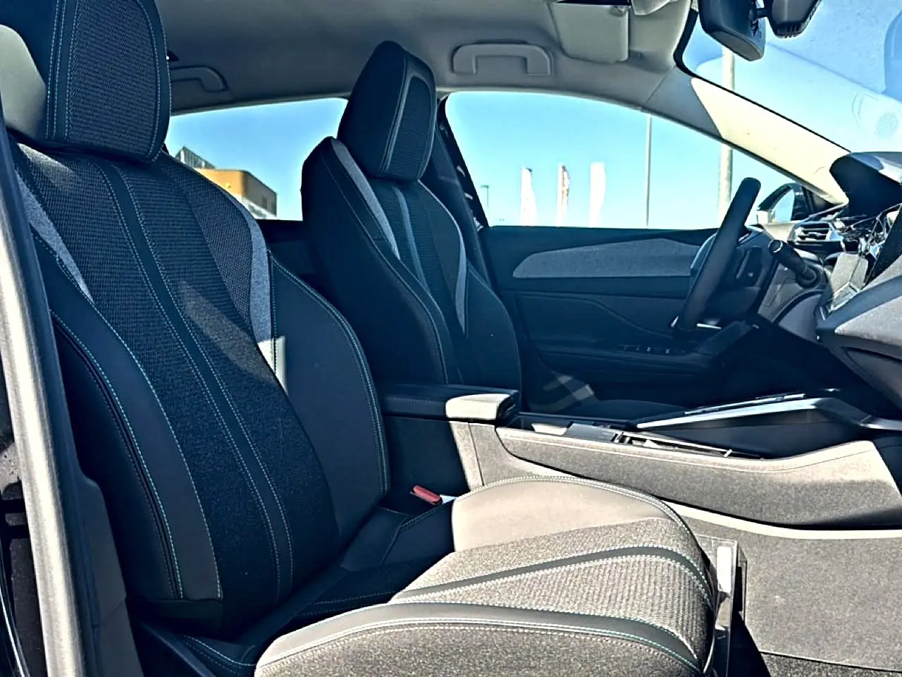 Vue intérieure côté gauche du Peugeot 408 Hybrid 145 allure e-dcs6 2025, sièges tissu noir et console centrale.