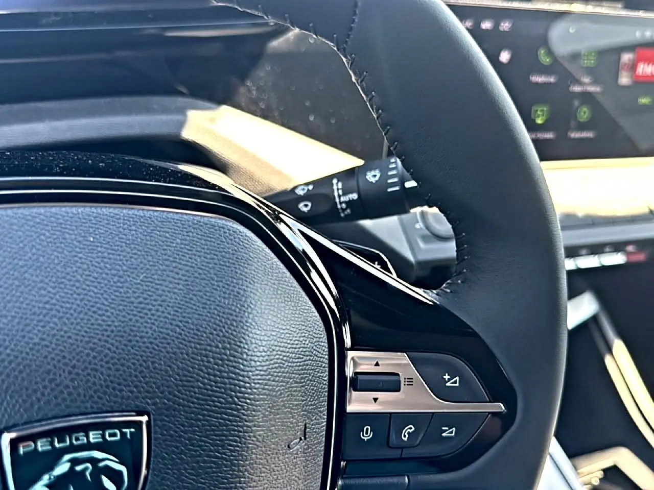 Gros plan sur le volant cuir noir du Peugeot 408 Hybrid 145 allure, avec commandes audio et téléphone intégrées.