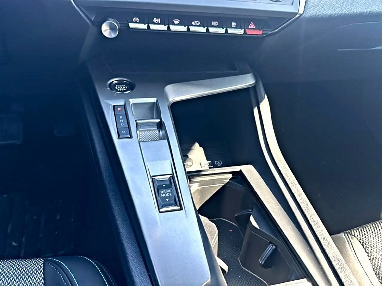 Vue rapprochée de la console centrale intérieure de la Peugeot 408 Hybrid 145 allure 2025 avec commandes de boîte auto et bouton Drive Mode.