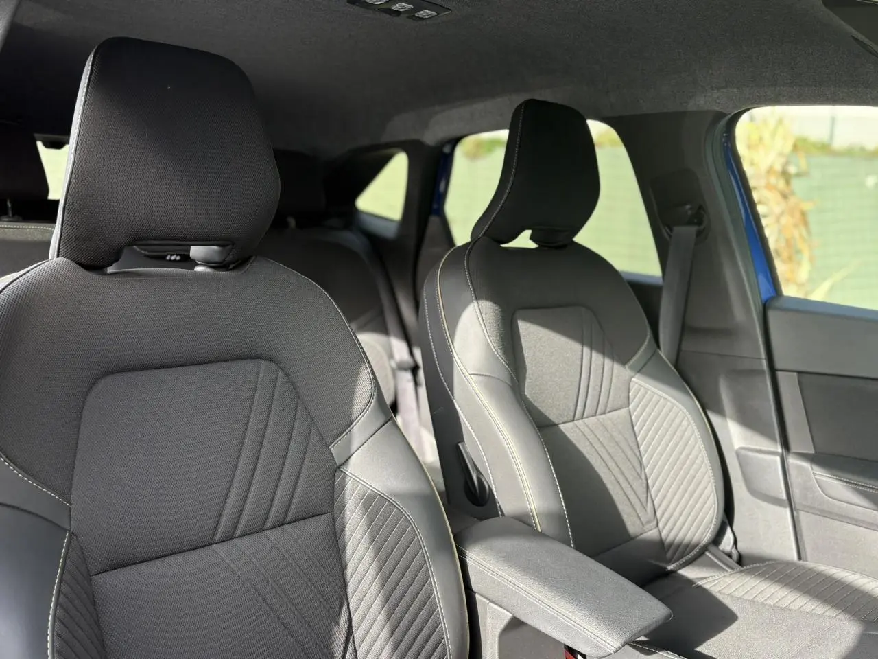 Vue intérieure sur les sièges avant en tissu et cuir noir avec surpiqûres claires du Renault Symbioz Bleu Iron.