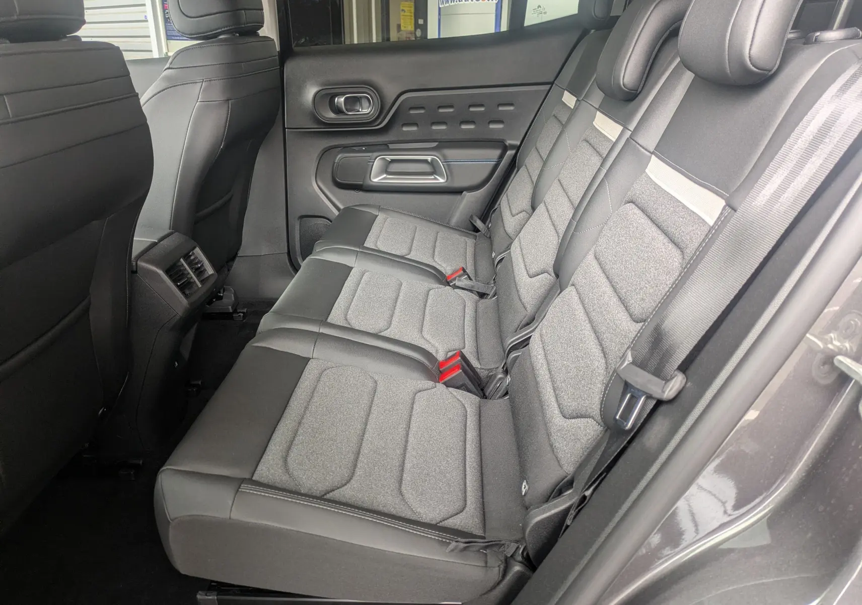 Vue latérale intérieure des sièges arrière gris tissu et TEP du Citroën C5 Aircross hybride 2025, avec ceinture et porte côté droit.