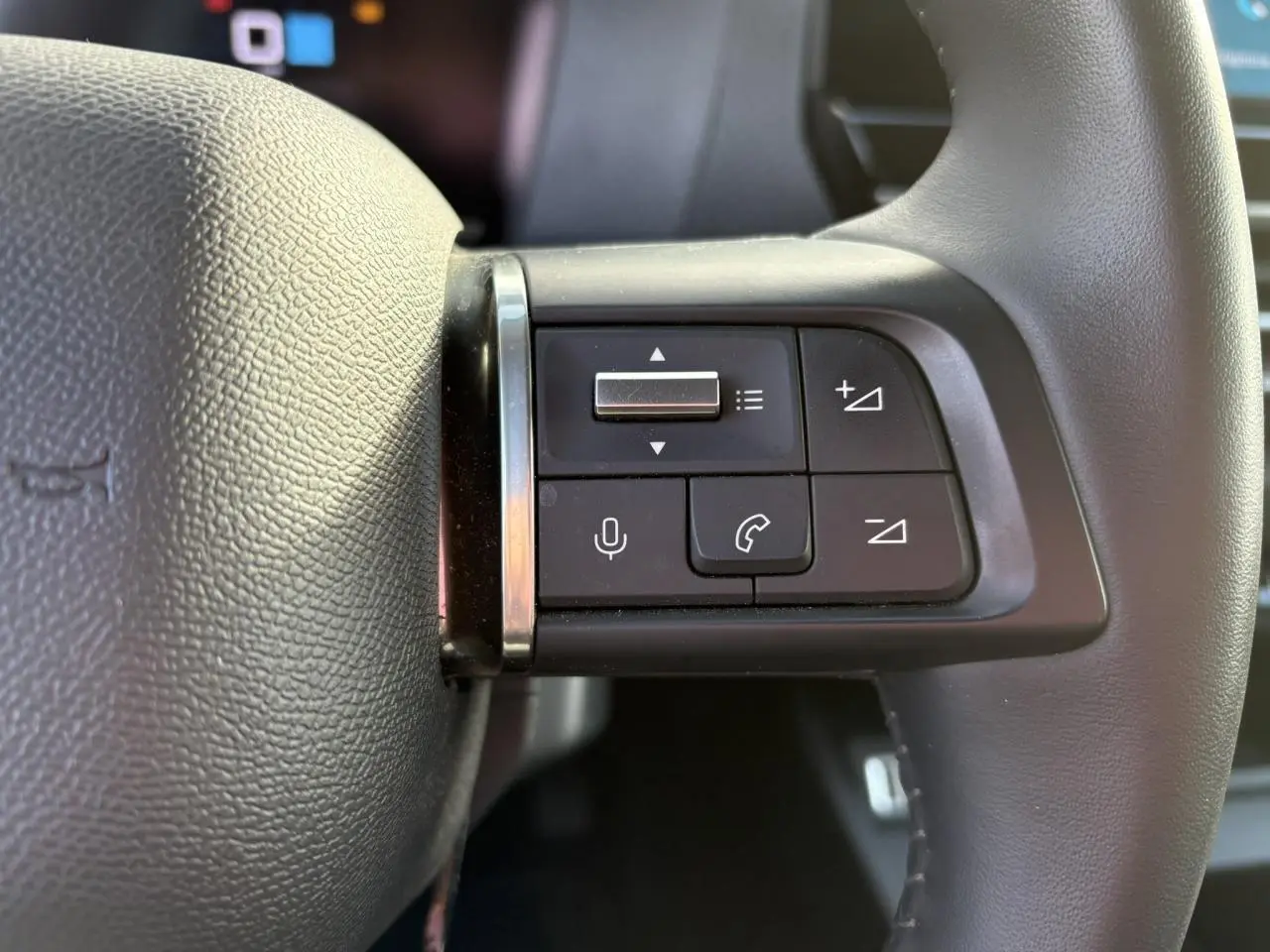 Gros plan sur les commandes audio et téléphone au volant cuir gris du Citroën C4 PureTech 130 2024.