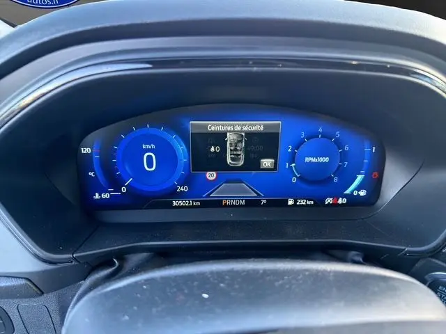 Vue rapprochée du tableau de bord numérique bleu de la Ford Focus 1.5 EcoBoost 150ch ST-Line BVA 2022, affichant la vitesse et les RPM.