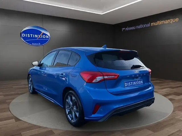 Vue 3/4 arrière droite d'une Ford Focus 1.5 EcoBoost ST-Line bleue 2022 avec jantes alliage et toit noir contrasté.