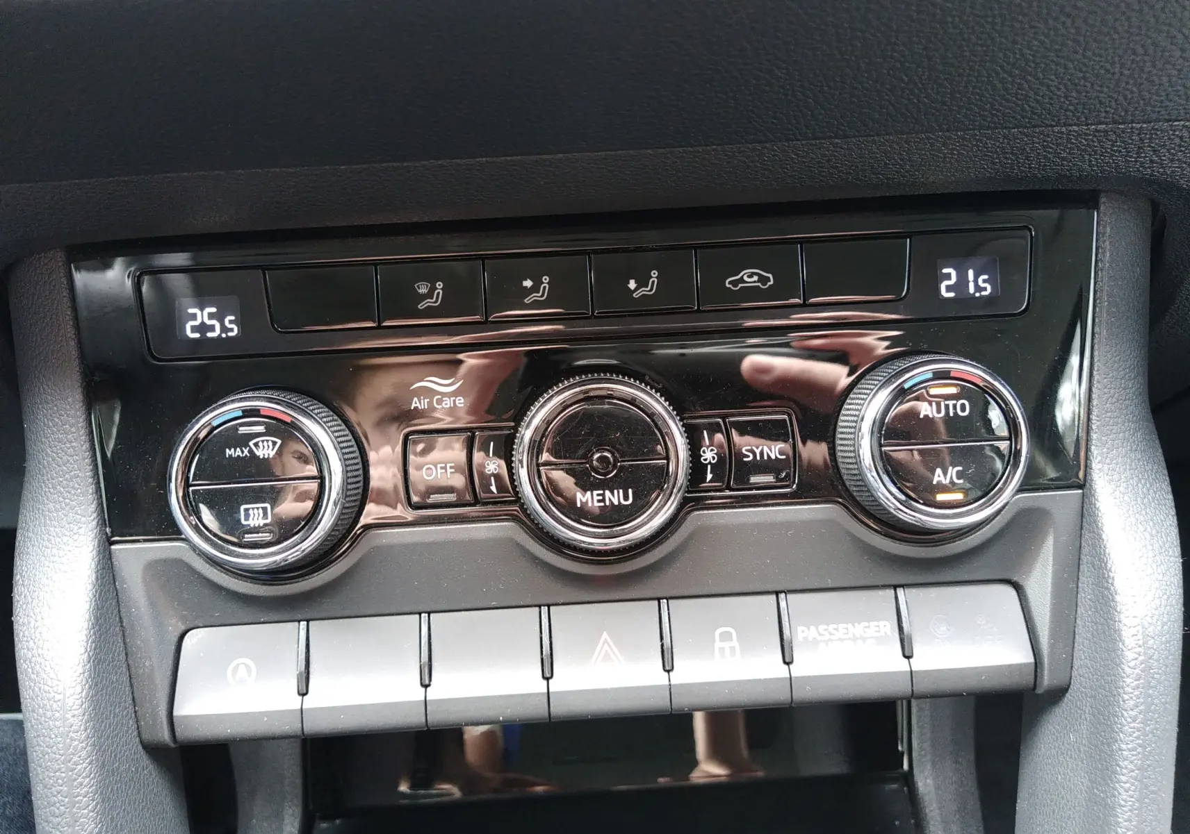 Gros plan sur la console de climatisation du Skoda Karoq gris, avec réglages digitaux et boutons rotatifs visibles.