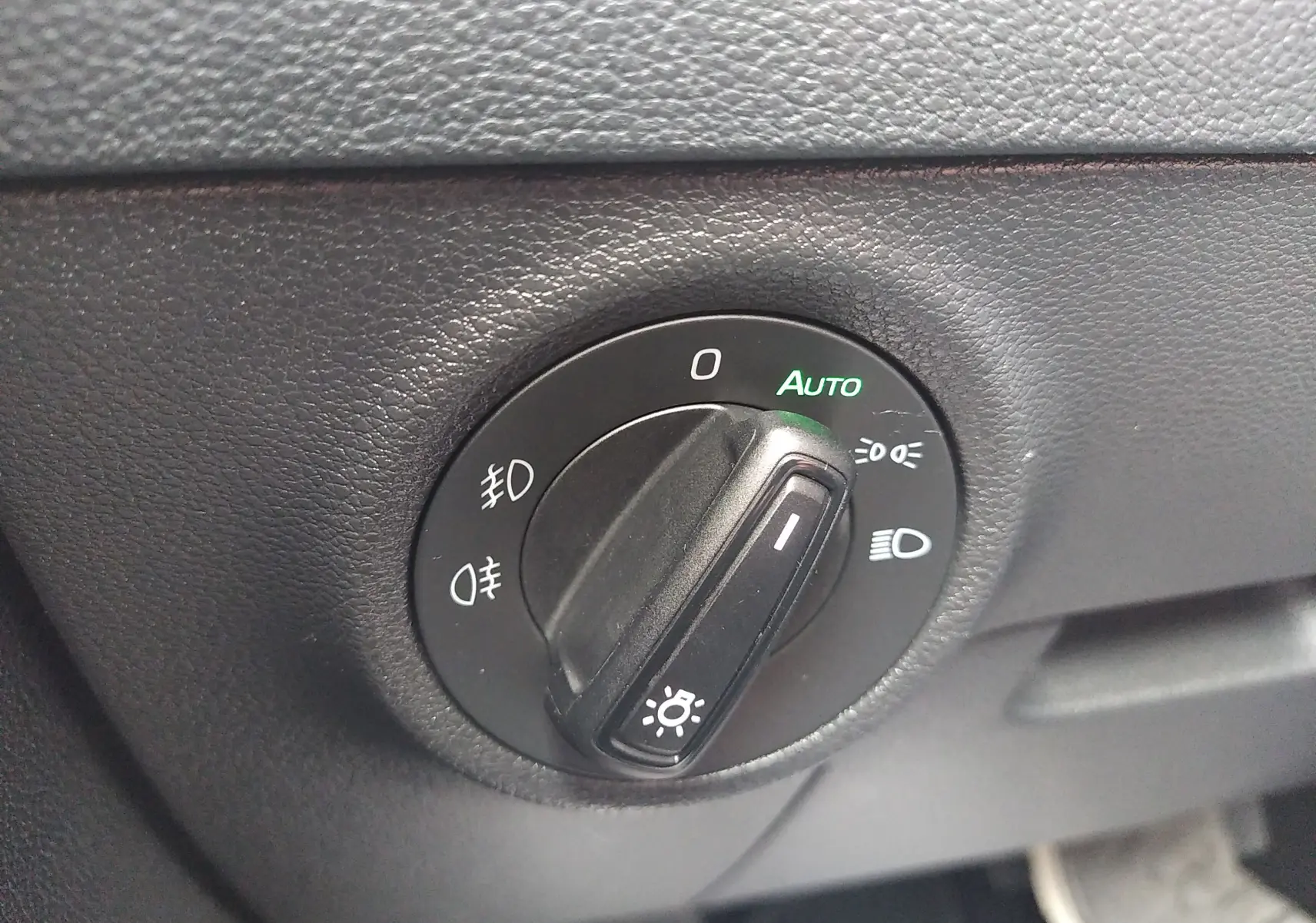 Gros plan sur le bouton de commande des phares du Skoda Karoq gris, avec mode automatique activé.