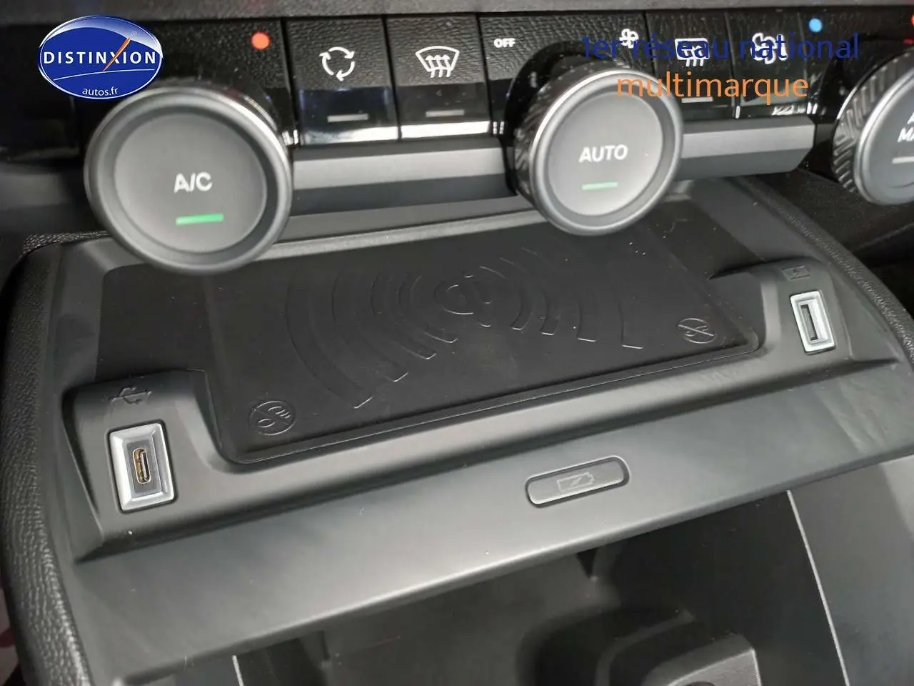 Vue rapprochée de la console centrale du Citroën C4 X 2023 avec commandes climatisation et chargeur sans fil.