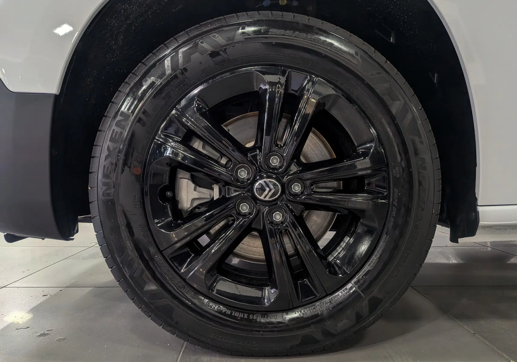 Gros plan sur la roue avant droite noire brillante du Citroën Berlingo Blanc Glacier 2025 avec jante stylée Pack Style.