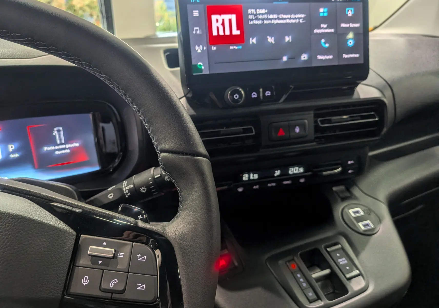 Vue intérieure du tableau de bord et volant du Citroën Berlingo blanc, avec écran tactile affichant la radio RTL.