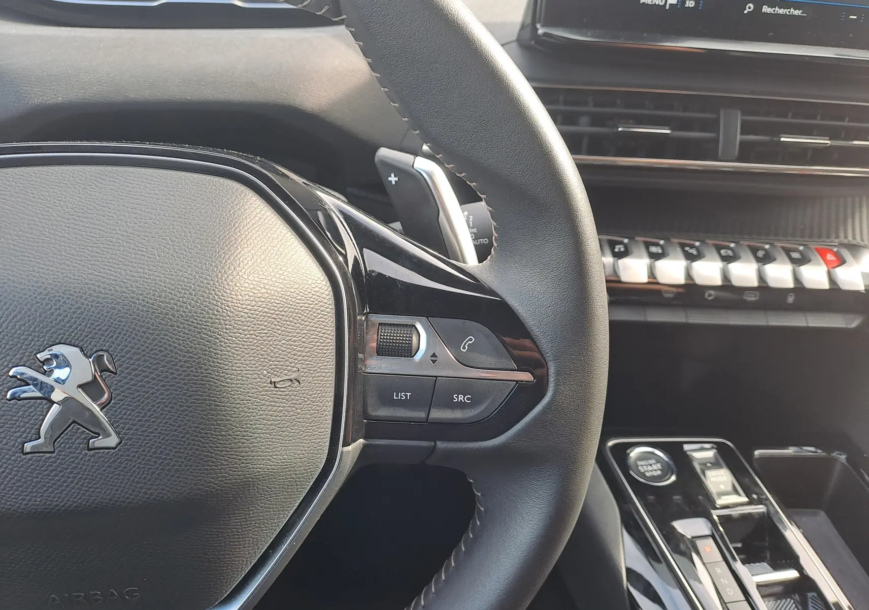 Vue rapprochée du volant et de la console centrale du Peugeot 3008 Hybrid 145 gris platinium, avec commandes au volant et écran tactile.