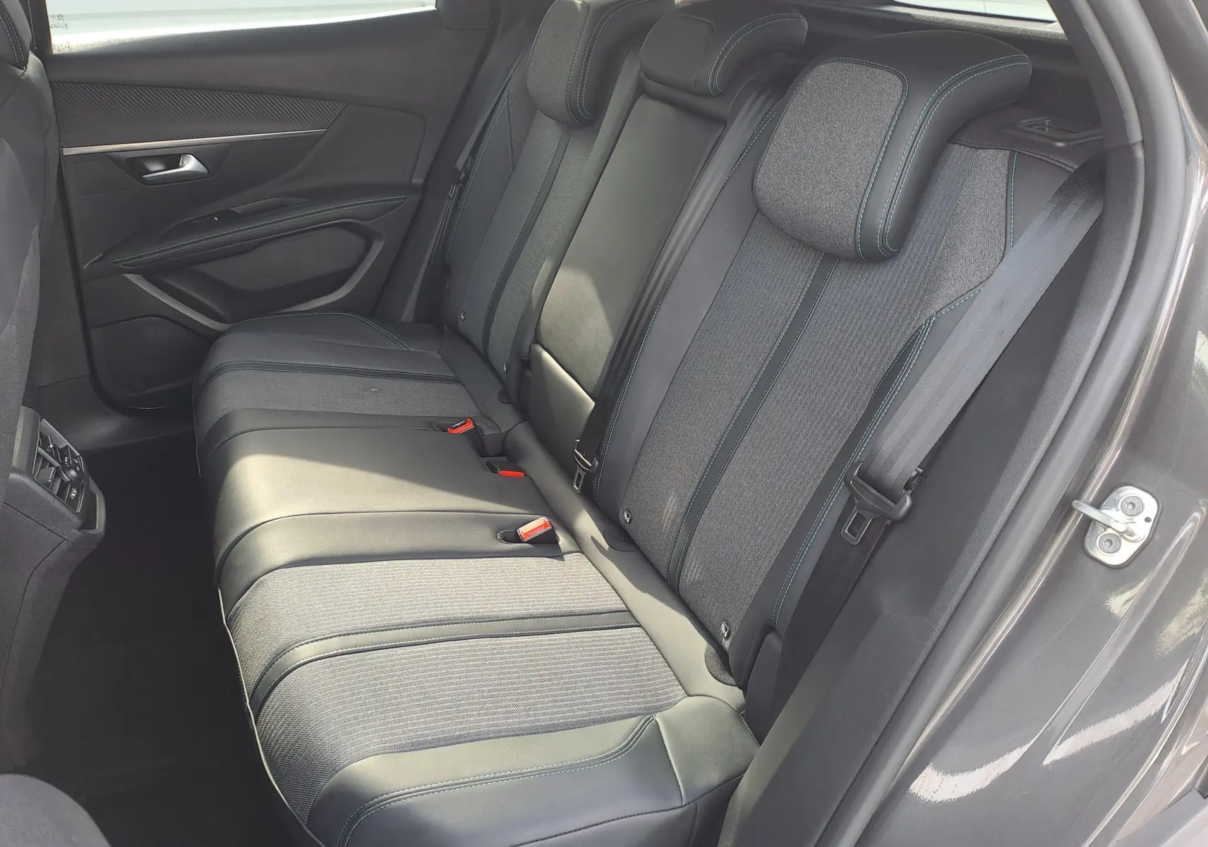 Vue côté droit des sièges arrière gris et noirs du Peugeot 3008 Hybrid 145 Allure Pack 2024 avec surpiqûres bleues.