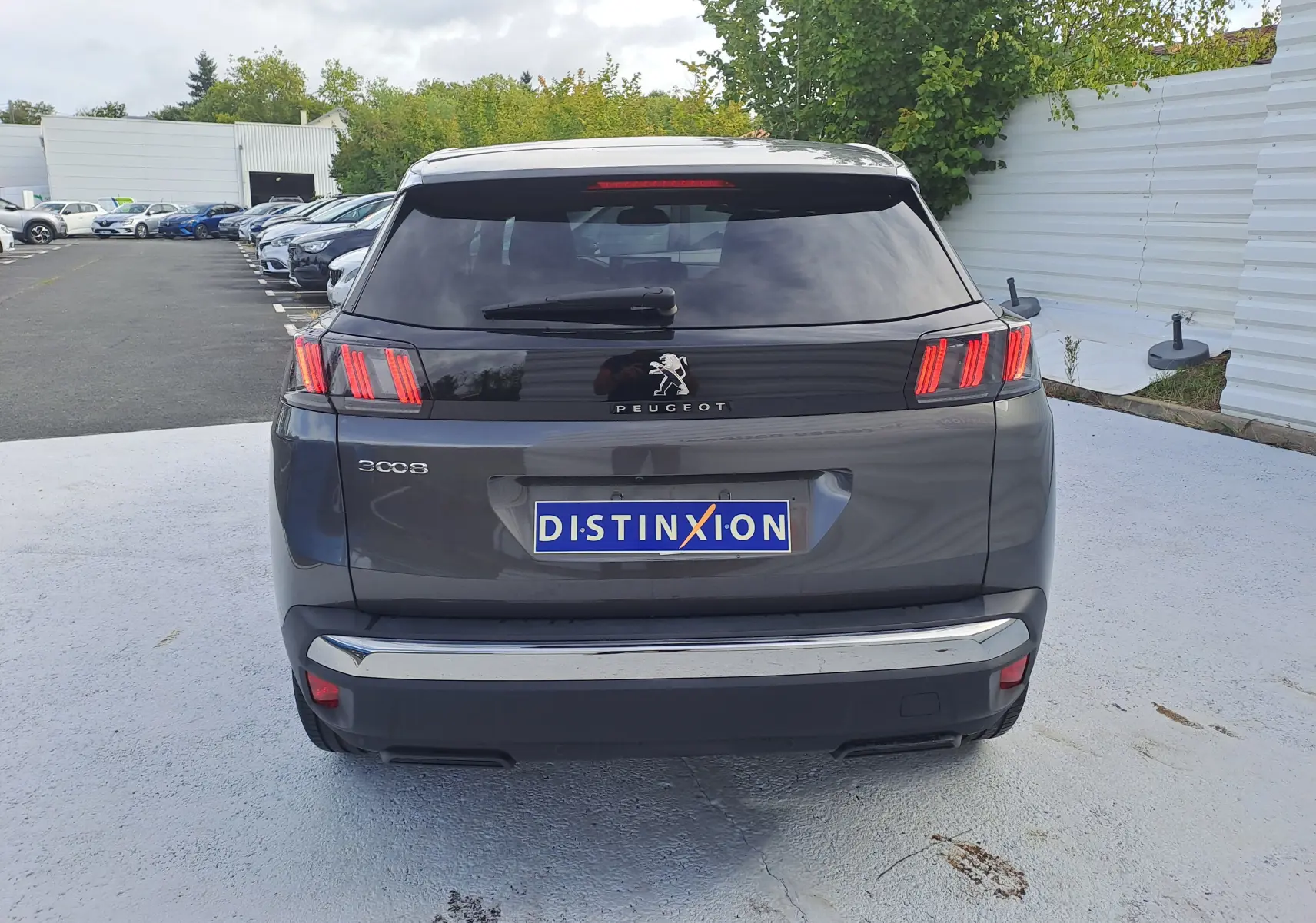 Vue arrière d'un Peugeot 3008 gris platinium 2024 avec feux arrière à trois griffes caractéristiques et plaque Distinxion.