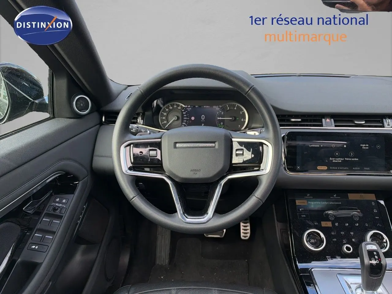 Intérieur du Range Rover Evoque 2023 en Santorini Black, vue centrée sur le volant et la console tactile moderne.
