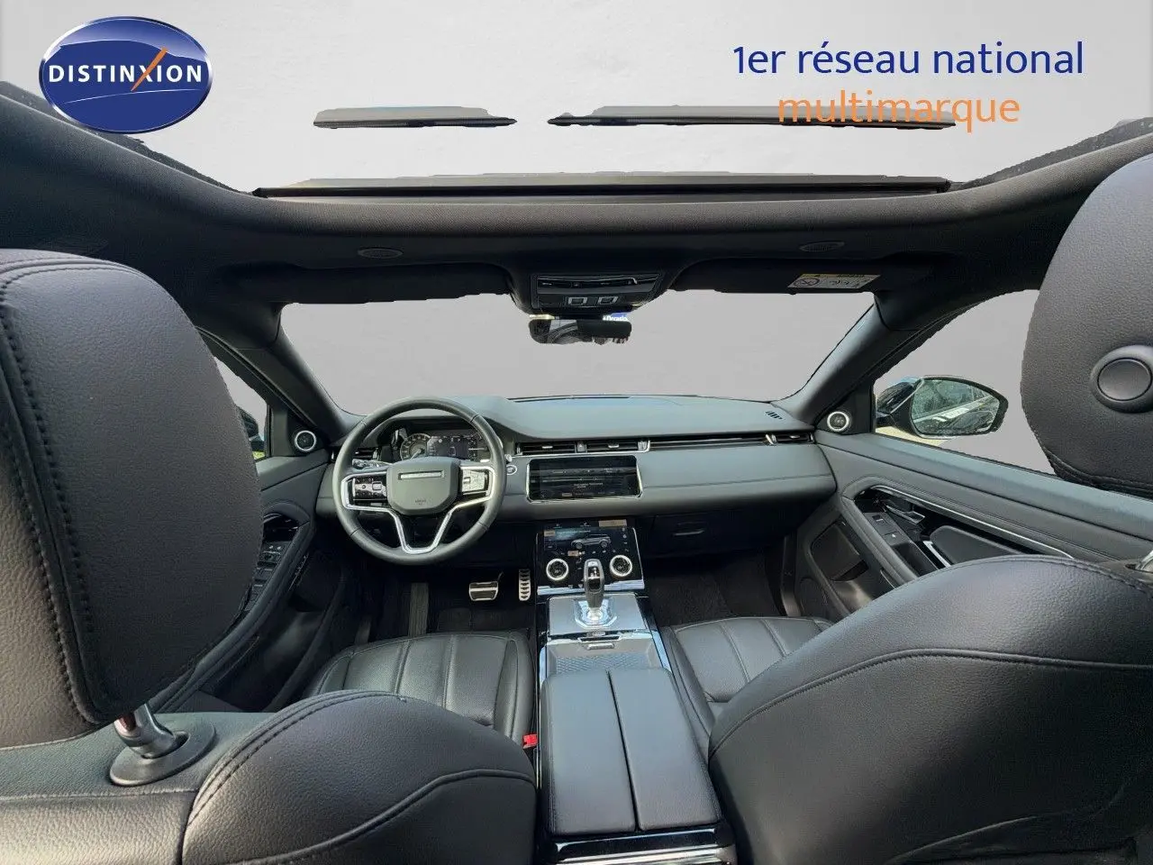Vue intérieure avant du Range Rover Evoque 2023 noir, montrant le tableau de bord, le volant et la console centrale en cuir.