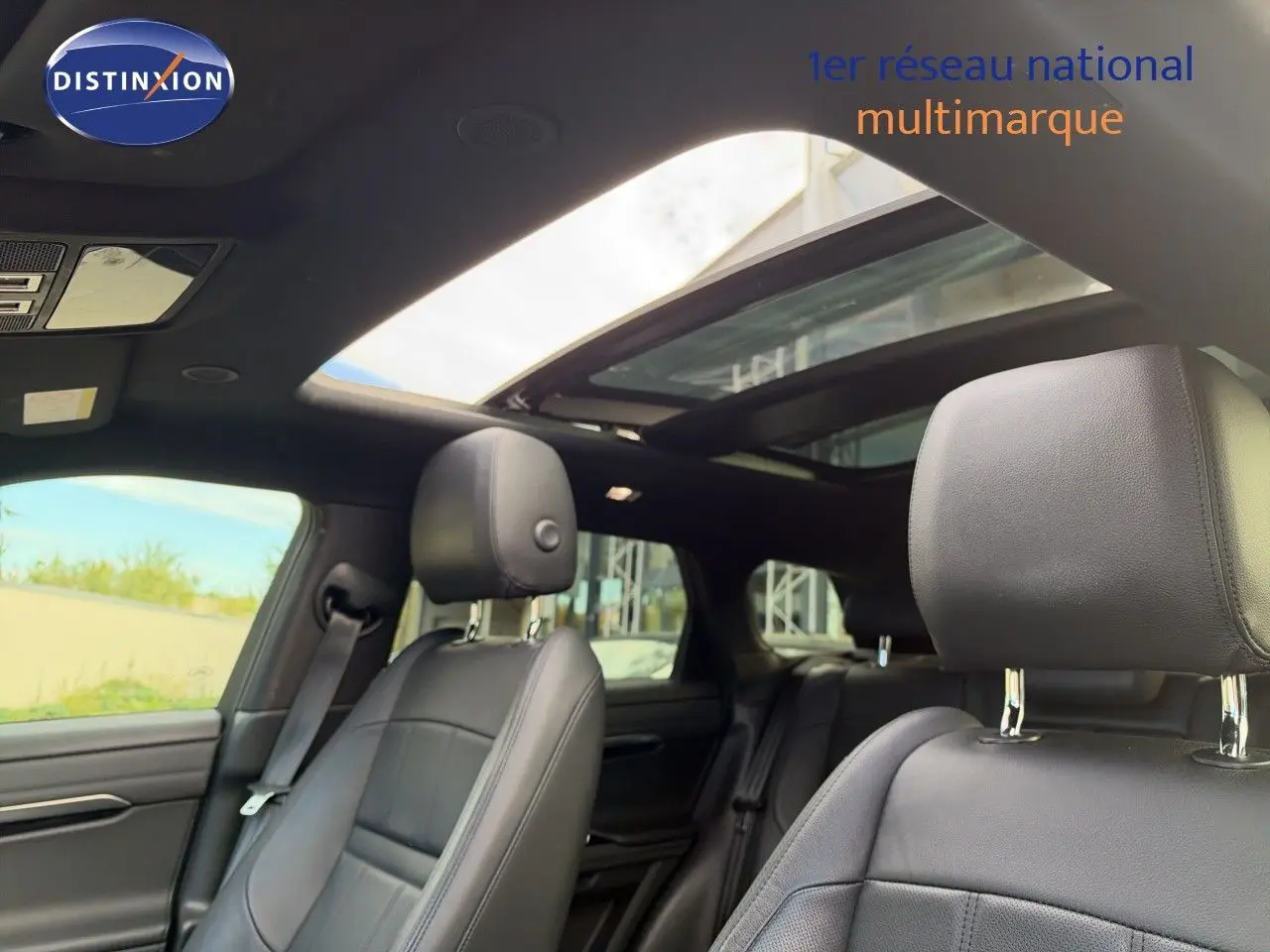 Intérieur du Range Rover Evoque 2023 en cuir noir, vue des sièges avant avec toit ouvrant panoramique ouvert.