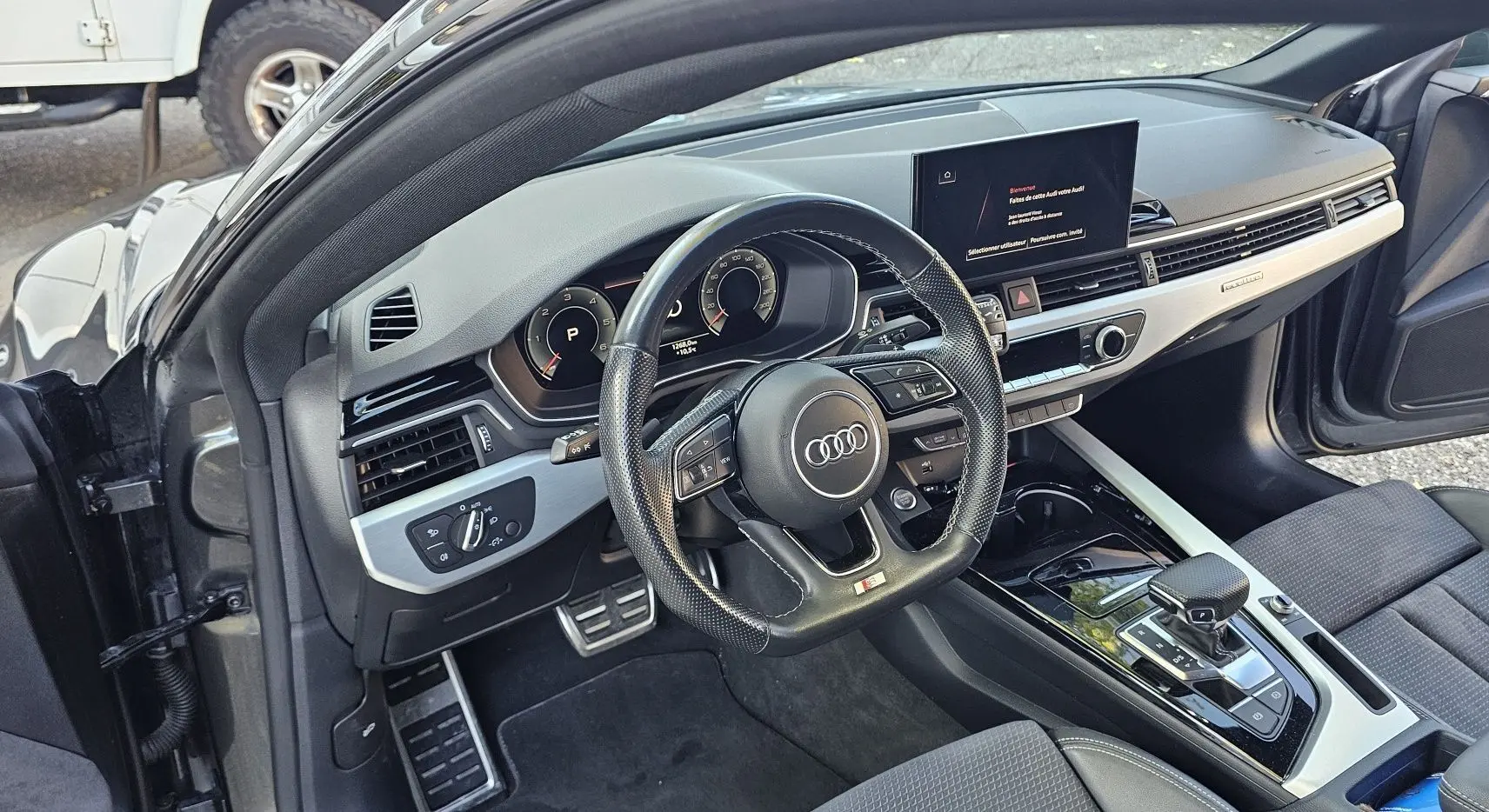 Intérieur de l'Audi A5 Sportback 2022 vu côté conducteur, volant sport en cuir perforé et tableau de bord moderne.