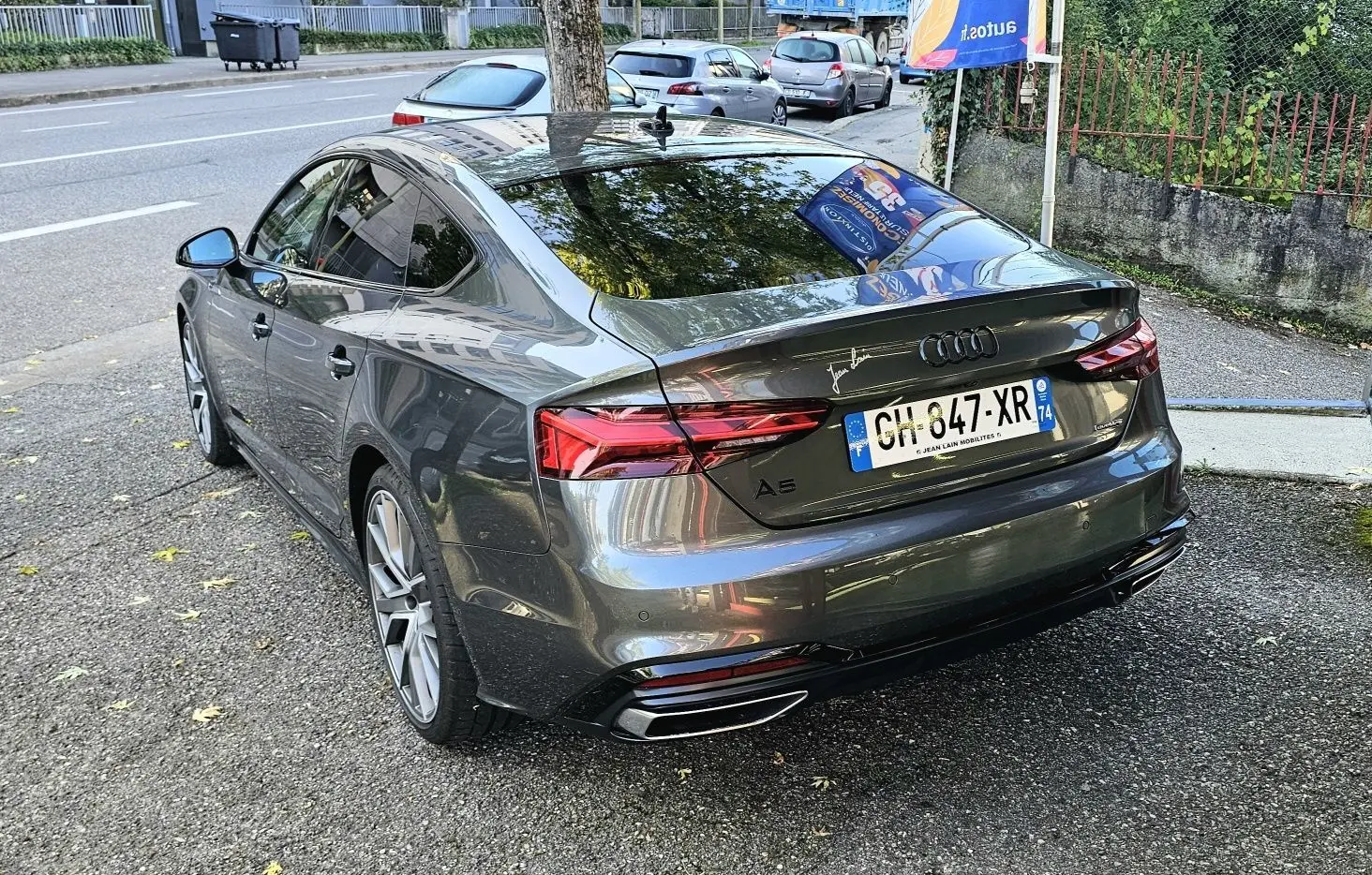 Vue 3/4 arrière droite d'une Audi A5 Sportback 2022 gris Daytona avec jantes alliage et feux LED distinctifs.