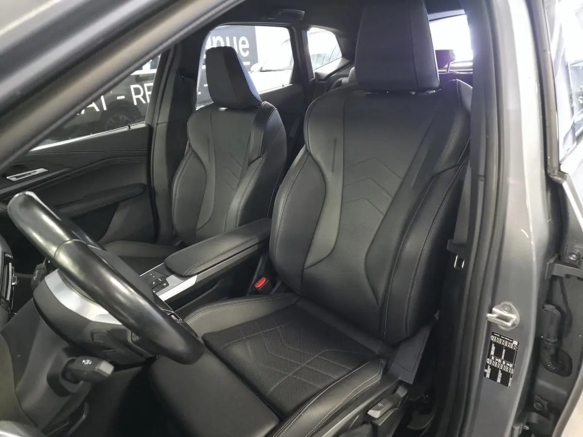 Vue intérieure côté conducteur de la BMW Série 2 218i M Sport 2023 avec sièges sport Similicuir noir et accoudoir central.