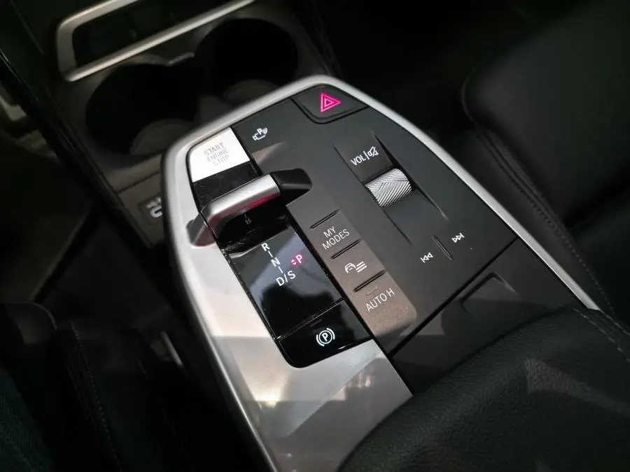 Gros plan sur la console centrale noire et argentée du BMW Série 2 218i Active Tourer avec commandes de boîte auto et volume.