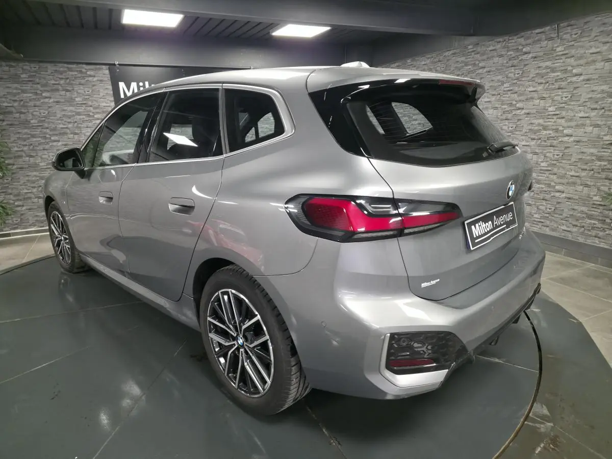 BMW Série 2 218i Active Tourer gris métallisé vue 3/4 arrière droit avec jantes bicolores et feux LED arrière
