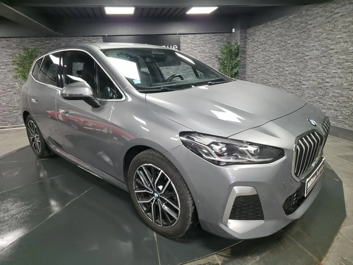 BMW Série 2 218i Active Tourer gris métallisé vue 3/4 avant avec calandre chromée et jantes M bicolores.