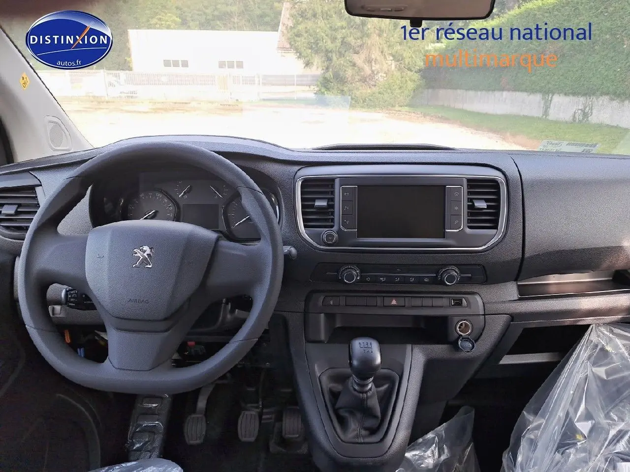 Vue intérieure avant du Peugeot Expert Blanc Kaolin 2023, tableau de bord avec volant, écran tactile et levier de vitesse manuel.