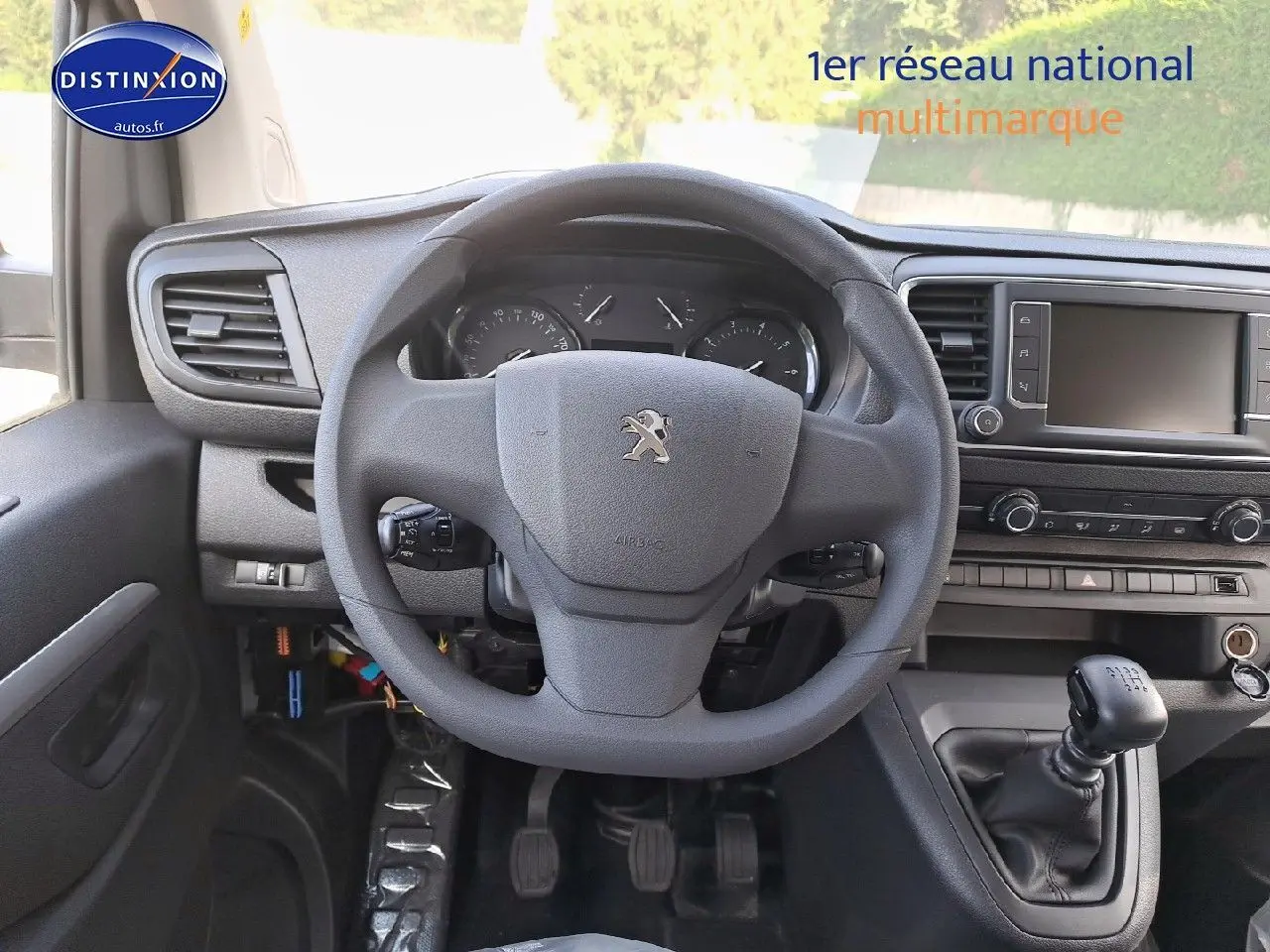 Vue intérieure centrée sur le volant Peugeot et la console avec levier de vitesses manuelle du Expert blanc Kaolin 2023.